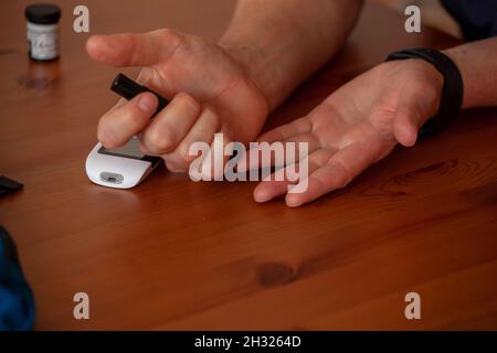 Gros plan d'un homme prenant du sang de son doigt sur une table en bois Banque D'Images