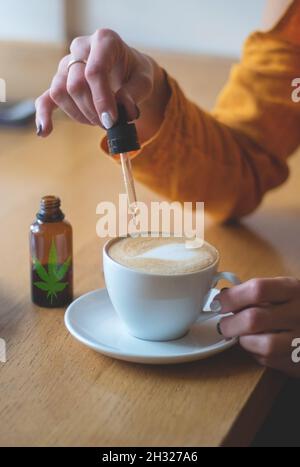 Femme utilisant des plantes de cannabis dans des boissons.Ajouter de l'huile de CBD dans une tasse de café.le concept de l'utilisation de la marijuana médicale. Banque D'Images