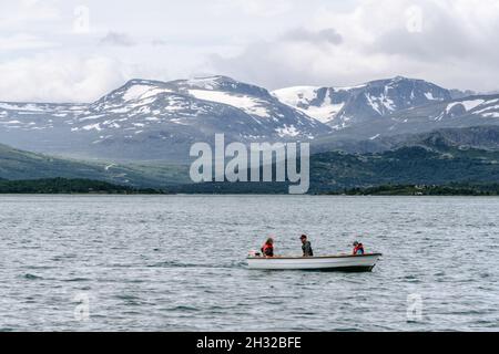 Amis pêchant à partir d'un bateau au coucher du soleil dans la rivière gjende à jotunheimen norvège Banque D'Images