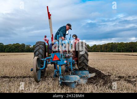 Homme conduisant un tracteur d'époque dans un match de labour dans un champ de chaume, East Lothian, Écosse, Royaume-Uni Banque D'Images