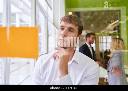 Jeune homme d'affaires regardant attentivement les notes collantes dans l'atelier de brainstorming Banque D'Images