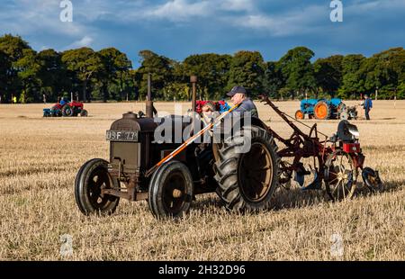 Homme conduisant un tracteur Fordson d'époque dans un match de labour dans un champ de chaume, East Lothian, Écosse, Royaume-Uni Banque D'Images