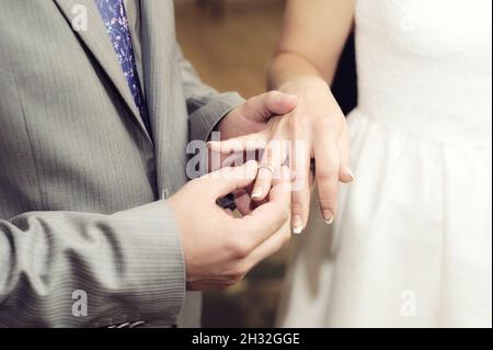 Échange d'anneaux de mariage.Cérémonie de mariage.Marié met sur l'anneau de mariage doré au doigt de la mariée, gros plan.Mariée et marié, jeunes mariés. Banque D'Images