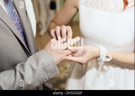 Cérémonie de mariage.Échange d'anneaux de mariage.Mariée met sur l'anneau de mariage doré au doigt de marié, gros plan.Mariée et marié, jeunes mariés. Banque D'Images