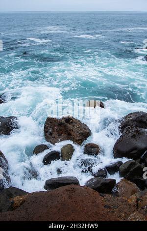 L'eau s'écrasant sur la côte rocheuse avec une ligne d'horizon en arrière-plan, vague éclaboussant contre des pierres sur la rive de près, éclaboussures d'eau, belle vue Banque D'Images