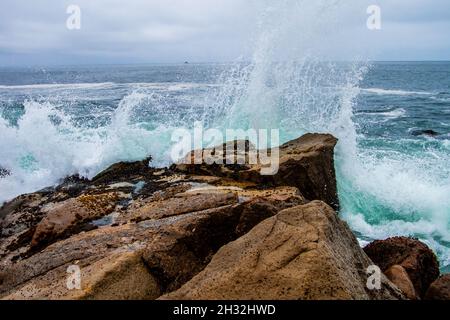 Vagues éclaboussant contre des pierres sur le rivage en gros plan, l'eau s'écrasant sur le rivage rocheux, éclaboussures d'eau, vue imprenable, eau claire bleu cyan Banque D'Images