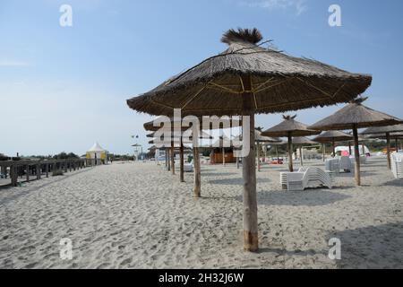 Gros plan d'une rangée de parasols de plage de paille contre un ciel bleu par une journée ensoleillée en Roumanie Banque D'Images