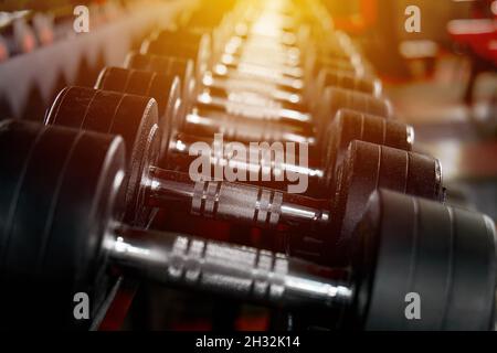 Rack avec de nombreuses tailles différentes d'haltères dans la salle de gym.Zone de poids libre.La lumière du soleil entre dans la fenêtre.Flou de mise au point.Copier l'espace Banque D'Images