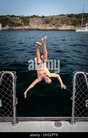 Homme sautant du bateau à voile dans l'océan à Rio de Janeiro, au Brésil Banque D'Images