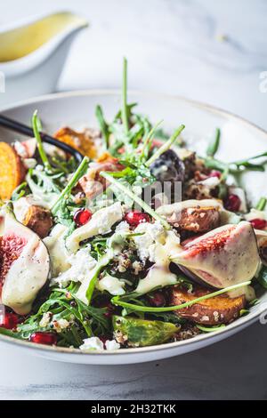 Salade chaude de quinoa d'automne avec légumes cuits au four (patate douce, choux de Bruxelles), figues, feta et grenade, gros plan. Banque D'Images