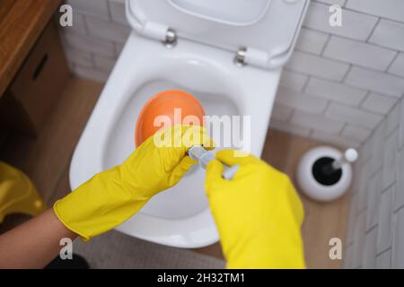 Les mains en gants tiennent un piston aux toilettes, en gros plan Banque D'Images