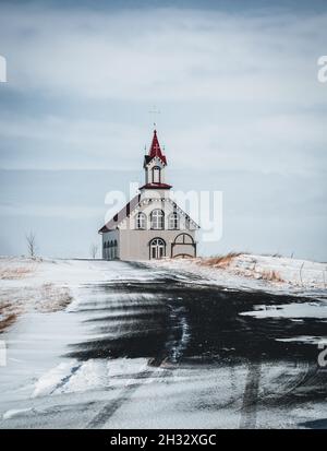 Église islandaise rurale typique sous un ciel bleu nuageux en hiver avec de la neige.Tir horizontal. Banque D'Images