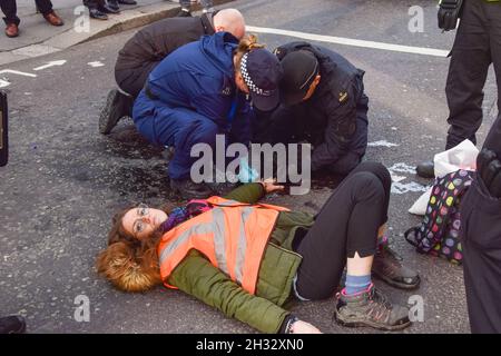 Londres, Royaume-Uni.25 octobre 2021.Les policiers dissolvent la colle sur la main d'un manifestant au cours de la manifestation. Isolez les manifestants de Grande-Bretagne se sont collés à la route et ont bloqué Wormwood Street et Bishopsgate, près de la gare de Liverpool Street.La manifestation est d’exiger du gouvernement qu’il isole toutes les maisons du Royaume-Uni d’ici 2030 afin de réduire les émissions de carbone.Crédit : SOPA Images Limited/Alamy Live News Banque D'Images