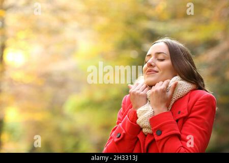 Une femme heureuse en rouge vêtue chaleureusement en automne dans un parc Banque D'Images