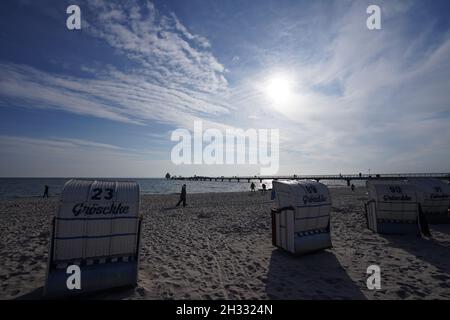 25 octobre 2021, Schleswig-Holstein, Grömitz: Les piétons marchent le long de la plage de la mer Baltique derrière les chaises de plage.Photo: Marcus Brandt/dpa Banque D'Images