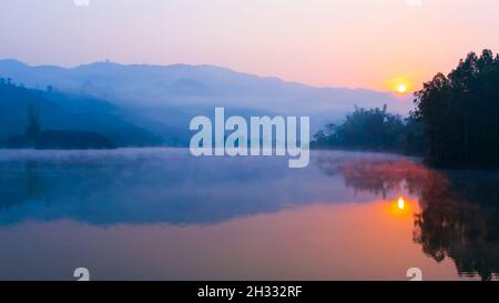 Paysage du lac Pa Khong au lever du soleil, un léger brouillard matinal couvre le lac et les montagnes en arrière-plan.Dien bien Phu, Vietnam. Banque D'Images