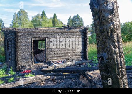 Une vieille maison en rondins brûlée dans le village lors d'une belle journée d'été contre le ciel bleu. Gros plan Banque D'Images