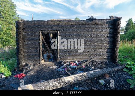 Une vieille maison en rondins brûlée dans le village lors d'une belle journée d'été contre le ciel bleu. Gros plan Banque D'Images