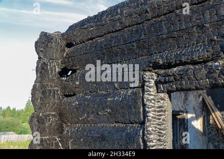 Une vieille maison en rondins brûlée dans le village lors d'une belle journée d'été contre le ciel bleu. Gros plan Banque D'Images