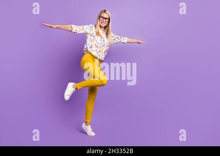 Photo de drôle adorable femme mûre habillé imprimer chemisier verres marche espace vide bras côtés sourire isolé couleur violet fond Banque D'Images