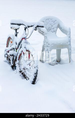 Vélo recouvert de neige par quelques chaises en hiver Banque D'Images