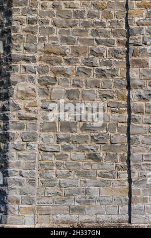 Vieux mur gris d'un ancien château en pierre naturelle par une journée ensoleillée. Surface plane. Ombres dures. Gros plan. Banque D'Images