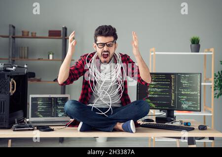 Portrait d'un sympathique fou en colère mal désespéré gars frustré hacker assis sur une table hurissant à la station de travail à l'intérieur Banque D'Images