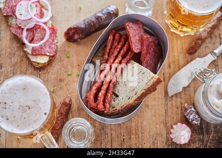 Vue de dessus de différents types de saucisses et de pain servi sur une table en bois avec couteau et bière Banque D'Images