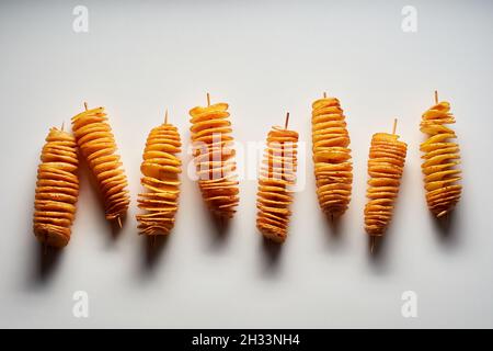 Vue de dessus de délicieuses frites tornado frits ou de pommes de terre sur des brochettes sur une surface blanche Banque D'Images