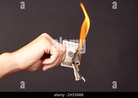 L'homme tient à brûler des billets de cent dollars. Banque D'Images