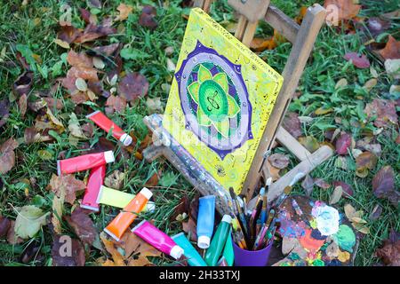 Chevalet avec peintures et peinture sur toile dans le parc d'automne. Banque D'Images