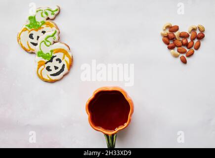 Halloween fond créatif : tasse de citrouille et biscuits faits maison en forme de citrouilles mignonnes et coeur d'amandes.Concept Trick or Treat.Esthétique automne Banque D'Images