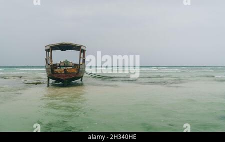Des bancs de sable d'atoll peu profonds avec un bateau de pêche solitaire sur la plage de Nungwi à marée basse dans l'océan Indien sur l'île de Zanzibar, Tanzanie. Pays exotiques tra Banque D'Images