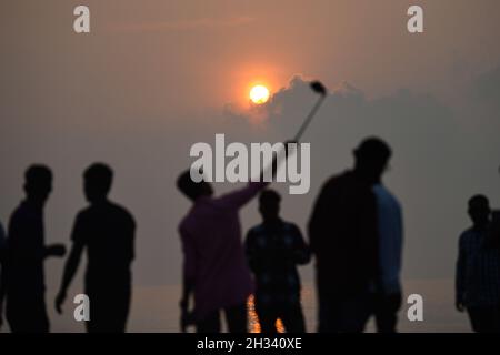 Patuakhali, Bangladesh.22 octobre 2021.Les touristes apprécient le soleil levant à la plage de Kuakata dans le district de Patuakhali du Bangladesh.Kuakata est l'un des rares endroits naturels qui offre une vue complète de la montée et le coucher du soleil sur la baie du Bengale.Une destination touristique populaire, il est à environ 320 kilomètres au sud de Dhaka, la capitale du Bangladesh.Crédit : SOPA Images Limited/Alamy Live News Banque D'Images