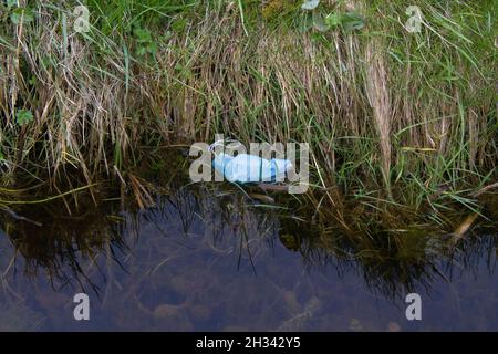 Jeté inlassablement le masque de visage flottant dans un fossé Banque D'Images