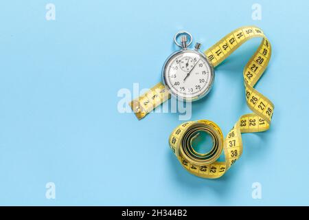 Roulette et chronomètre.Concept de régime et de forme physique.Arrière-plan bleu.Espace de copie de modèle pour le texte. Banque D'Images