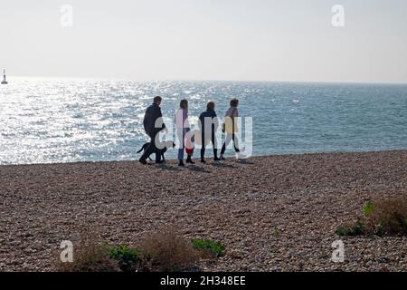 Famille personnes avec chien marchant sur la plage de galets et vue sur la mer brillante en automne octobre Dungeness Kent Angleterre Grande-Bretagne Royaume-Uni KATHY DEWITT Banque D'Images