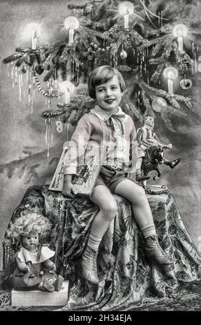 Joyeux enfant avec un arbre de Noël, des cadeaux et des jouets vintage.Image ancienne avec grain de film original Banque D'Images