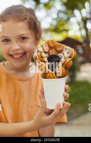 La petite fille profite d'une gaufre belge Banque D'Images