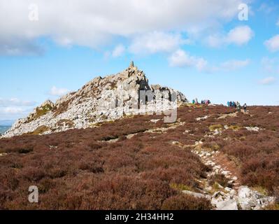 Walkers gather at the base of Manstone Rock, a quartzite outcrop and summit of the Stiperstones ridge (536m), Shropshire Hills AONB Stock Photo