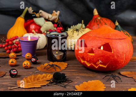 Citrouilles d'Halloween sur une table sombre en bois avec araignées, bougies, citrouilles, feuilles.La vie encore conceptuelle sur le thème de l'Halloween. Banque D'Images