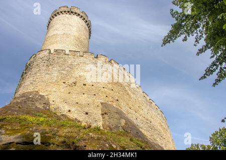 Tour circulaire en pierre derrière les murs avec les remparts d'un château gothique. Banque D'Images