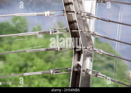 Vue rapprochée de l'élingue de blocage en acier et de la vis, détail du cadre sur pont en verre avec boucle en acier inoxydable de construction de fixation. Banque D'Images