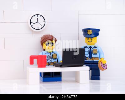 Tambov, Fédération de Russie - 17 octobre 2021 Lego policier et policier dans leur bureau de police travaillant sur un ordinateur portable. Banque D'Images