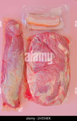 Viande de porc.morceaux de porc frais .aspirer la viande emballée sur fond rose.produits de viande. Banque D'Images