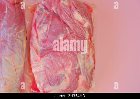 Viande de porc.morceaux de porc frais . texture de la viande.aspirer la viande emballée sur fond rose.produits de viande. Banque D'Images