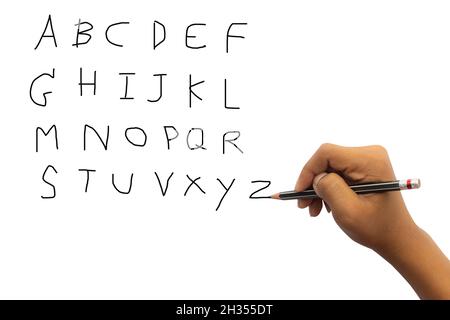 Gros plan de la main d'un enfant avec un crayon écrivant des mots Anglais A-Z à la main sur du papier blanc sur fond blanc, Un enfant apprenant à écrire des lettres. Banque D'Images