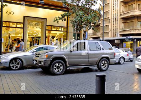 Les voitures passent devant les boutiques de la rue Hamra, dans le quartier de Hamra à Beyrouth, au Liban. Banque D'Images