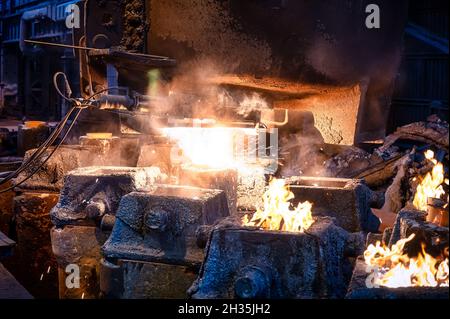 Le métal liquide est versé dans des moules en acier à partir de louches métallurgiques. Banque D'Images