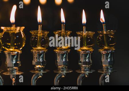 Les bougies Hanukkah sont illuminées dans une menorah décorée d'argent, sur un fond noir de la nuit - la fête juive de Hanukkah Banque D'Images